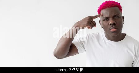 Gesto stupido. Uomo nero perplesso. Idea pazza. Sentimenti dispiacenti. Idea pazza. Scherzo. Confuso africano ragazzo con capelli rosa bianco t-shirt in mano Foto Stock