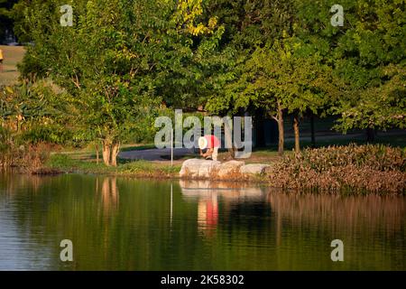 MUELLER PARK LAKE, AUSTIN, TEXAS/USA – AGOSTO 16 2019: Uomo che scavava nella sua borsa in tutta la banca. Foto Stock