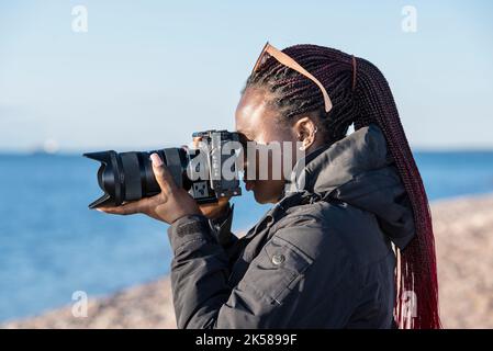 Fotografo hobbista africano fuori in natura e scattare foto con una fotocamera mirrorless Foto Stock