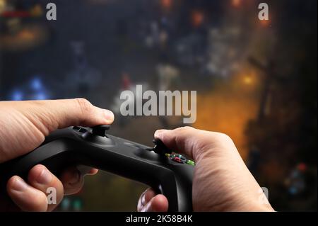 Videogiochi. Un giocatore tiene in mano un moderno joystick GAM22ICB. Gioca a giochi online su un grande schermo TV, personal computer. Nuove tecnologie, eport Foto Stock