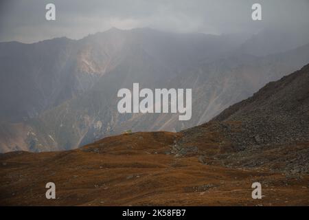 Piccola casa colorata alta in montagna durante la neve e la nebbia Foto Stock