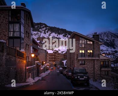 Strade strette e accoglienti e case e appartamenti moderni in pietra nel villaggio di El Tarter al crepuscolo o caduta di notte nei Pirenei, Grandvalira, Andorra Foto Stock