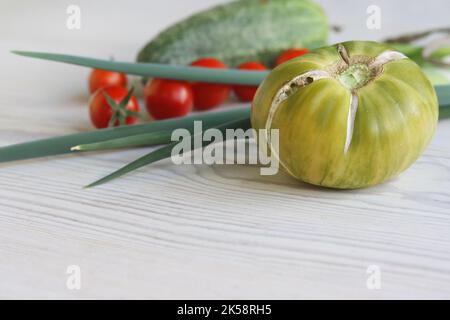 Set di verdure fresche da giardino. Cetriolo verde, pomodori ciliegini rossi, erba cipollina verde. Set con cibo crudo su sfondo di legno bianco. Concetto di cibo sano. Foto Stock