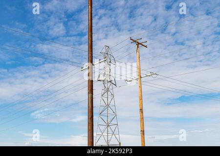 Torre di trasmissione dell'elettricità, pali di energia elettrica in legno e acciaio. Concetto di rete elettrica, infrastruttura e distribuzione. Foto Stock