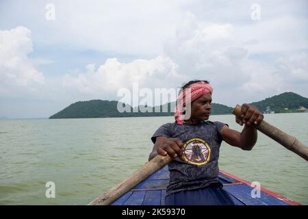 un povero uomo tribale che tira la barca con la mano con la pagaia Foto Stock