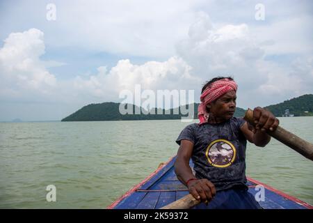 un povero uomo tribale che tira la barca con la mano con la pagaia Foto Stock