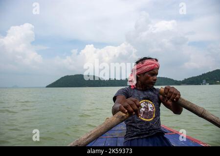 un povero uomo tribale che tira la barca con la mano con la pagaia Foto Stock