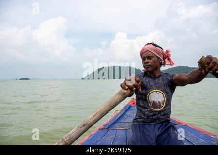 un povero uomo tribale che tira la barca con la mano con la pagaia Foto Stock