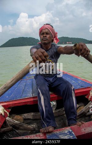 un povero uomo tribale che tira la barca con la mano con la pagaia Foto Stock