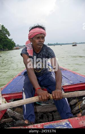 un povero uomo tribale che tira la barca con la mano con la pagaia Foto Stock