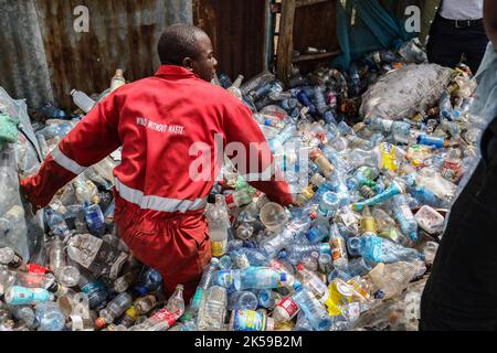 Kisumu, Nyanza, Kenya. 4th Ott 2022. Un uomo che indossa una società di coca-coca rossa complessivamente ricamata con le parole ''mondo senza rifiuti'' si vede lavorare in un centro di raccolta rifiuti di plastica a Kisumu. Attivisti e gruppi ambientalisti in Kenya e in altre parti del mondo hanno denunciato che la Coca-cola Company è stata nominata sponsor del vertice sul clima di quest'anno, COP 27, che si terrà a novembre in Egitto. (Credit Image: © James Wakibia/SOPA Images via ZUMA Press Wire) Foto Stock