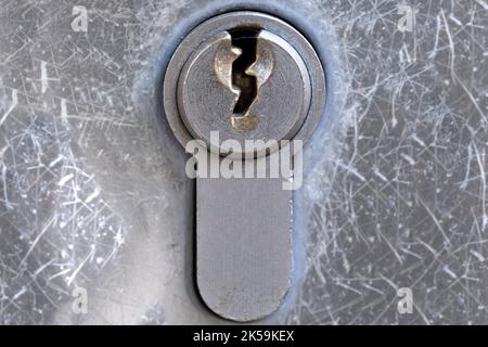 Piastra di metallo con foro per chiave di una serratura a cilindro in una porta. Isolato su sfondo grigio a grunge (metallo) Foto Stock