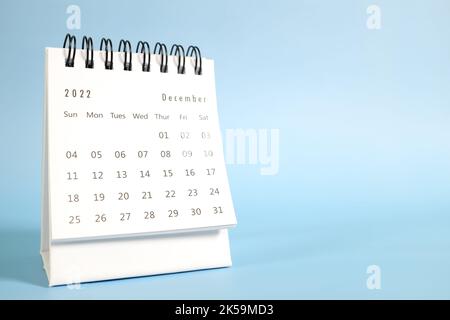 Focalizzazione selettiva del calendario da tavolo di dicembre 2022 su sfondo blu con albero di natale e spazio copia. Foto Stock