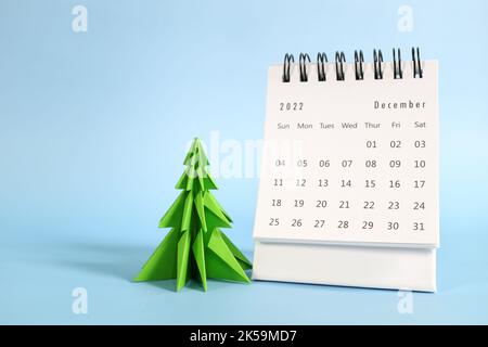 Focalizzazione selettiva del calendario da tavolo di dicembre 2022 su sfondo blu con albero di natale e spazio copia. Foto Stock