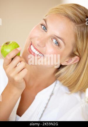 Ama uno spuntino sano. Ritratto di una giovane donna attraente sorridente con una mela in mano. Foto Stock