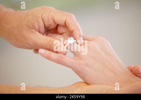 Un impegno che dura tutta la vita. Vista ritagliata di una mano mans che scorre un anello di nozze su un dito anello donna. Foto Stock