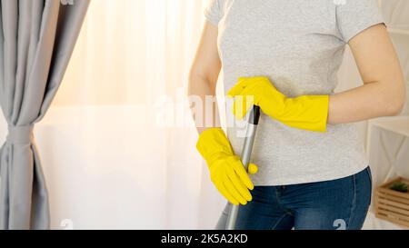 Pulizia della casa. Società di janitor. Servizio di casa. Lavoratore competente. Donna irriconoscibile in guanti di protezione che tengono mop per lavare pavimento luce int Foto Stock