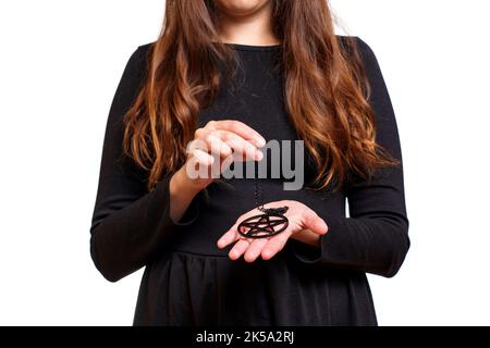 Donna che indossa un vestito nero tiene una grande collana pentagramma in mani isolate su sfondo bianco. Foto Stock