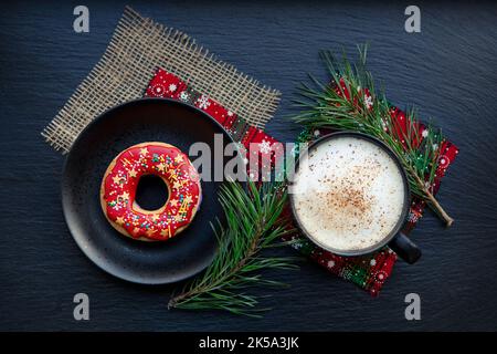Biscotti rossi di Natale e tazza di caffè su sfondo nero Foto Stock