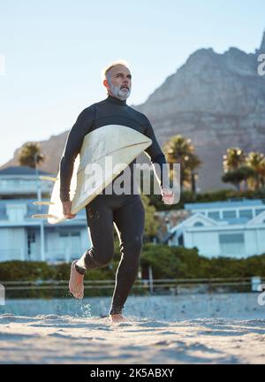 Spiaggia, surfista maturo che corre con surf board su sabbia di mare e sport acquatici fine settimana. Libertà, fitness e divertimento vacanza estiva in Australia Foto Stock