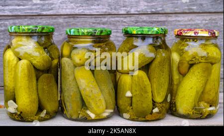 Vasetti di vetro con cetrioli decapati. Vasetti con verdure varie sottaceto. Il concetto di cibo in scatola in una composizione rustica. Foto Stock