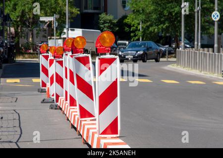 Barriere stradali rosse e bianche con torcia elettrica per assicurare un cantiere, lavori stradali, strade in costruzione. Recinzione temporanea, riparazione in città Foto Stock