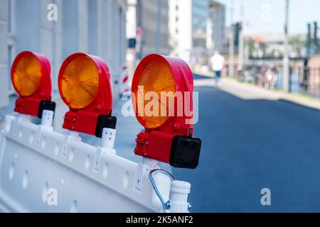 Barriere stradali rosse e bianche con torcia elettrica per assicurare un cantiere, lavori stradali, strade in costruzione. Recinzione temporanea, riparazione in città Foto Stock