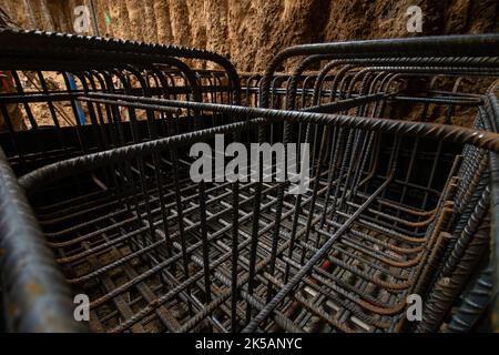 Gabbia di rinforzo-armatura di pozzo in terreno sabbioso in scavo seminterrato per fondazione di zattere in cemento armato Foto Stock