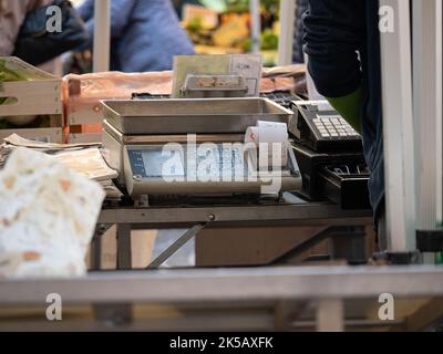 Bilance di precisione allegate a un registratore di cassa per la raccolta di contanti e l'emissione di ricevute in una bancarella del mercato ortofrutticolo. Foto Stock