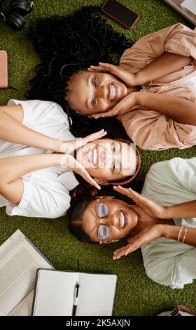 Studenti, studiando e diversità con giovani donne felici sdraiati insieme mostrando sorriso mentre al college per l'istruzione e l'apprendimento. Vista dall'alto verticale di Foto Stock