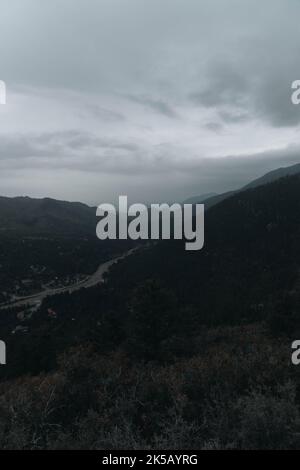 Una vista aerea nebbia di un'autostrada sotto i picchi di picchi di picchi con alberi in Colorado, tiro verticale Foto Stock