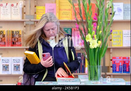 Cheltenham, Gloucestershire, Regno Unito – Venerdì 7th ottobre 2022 – Un visitatore sfoglierà i nuovi libri nella libreria del Cheltenham Literature Festival - il Festival si svolge fino a domenica 16th ottobre 2022. Foto Steven Maggio / Alamy Live News Foto Stock