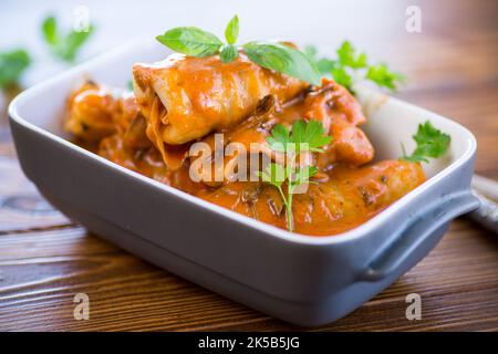 Cavolo farcito tradizionale con carne macinata e riso, servito in salsa di pomodoro su un tavolo di legno. Foto Stock