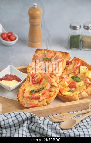 Pizza pane con gamberi, bastoncini di granchio, pomodori, salsiccia, formaggio in un vassoio di legno con salsa Foto Stock