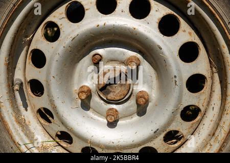vecchia ruota arrugginita alla luce del sole. cerchione ruota, bulloni e valvola schrader tappata. Primo piano Foto Stock