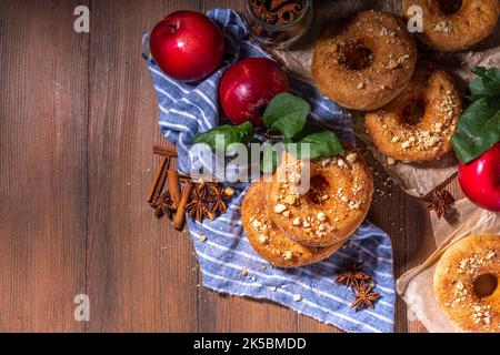 Tradizionali ciambelle di sidro di mele pronte da mangiare. Ciambelle alla cannella di mele cotte in casa con crumble di torta di mele e spezie, servite su copia da tavolo in legno Foto Stock