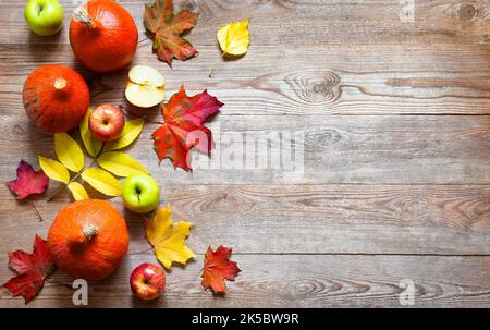 Autunno bordo da mele, zucca e foglie cadute su vecchio tavolo di legno. Halloween o concetto di giorno di ringraziamento. Zucca di ringraziamento con frutta. FRU Foto Stock