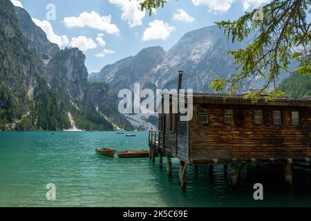 Una vista panoramica di una piccola casa in legno costruita su un lago con belle montagne sullo sfondo Foto Stock