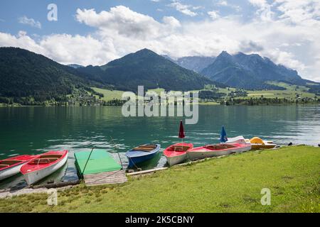 Barche sulla riva di Walchsee, sullo sfondo il Kaisergebirge con Ebersberg (1164 m), Heuberg (1603 m) e la catena montuosa del Kaiser Zahmen, Walchsee, Kaiserwinkl, distretto di Kufstein, Tirolo, Austria Foto Stock