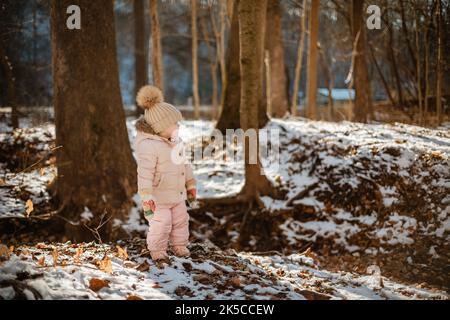 Bambina che esplora la foresta innevata in un insieme Foto Stock