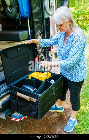 Donna che immagazzina l'ingranaggio del campeggio nella scatola del cambio di Radius Outfitters 500 Foto Stock