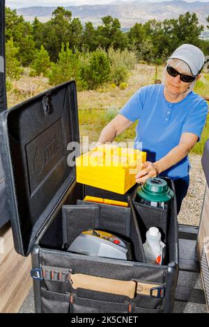 Donna che immagazzina l'ingranaggio del campeggio nella scatola del cambio di Radius Outfitters 500 Foto Stock