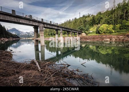 Italia, Veneto, provincia di Belluno, Domegge di Cadore. Lago cadore centrale, livello dell'acqua estremamente basso e accumulo di sporcizia e legno marciume sulla riva Foto Stock