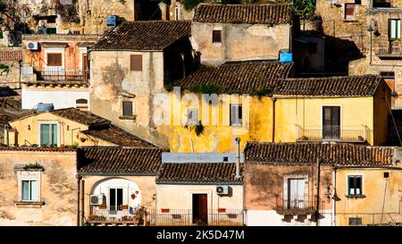 Italia, Sicilia, angolo barocco, città barocca, Modica, centro storico, edifici color ocra, tetti in tegole rosse, luce soffusa, senza cielo Foto Stock