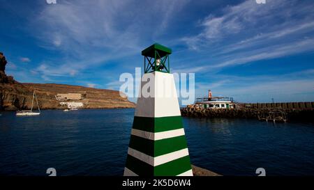 Spagna, Isole Canarie, Gran Canaria, Costa sud-occidentale, Puerto de Morgan, Piccola Venezia, ripresa grandangolare, faro quadrato verde e bianco in primo piano, barche in mezzo, costa rocciosa sullo sfondo, mare blu scuro, cielo blu con nuvole a strisce bianche Foto Stock