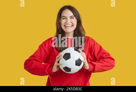 Ritratto di giovane donna allegra positiva che sta avendo divertimento cattura palla di calcio gettato a lei. Foto Stock