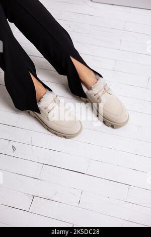 Stivali in pelle scamosciata beige autunnale da donna su gambe bellissime. Eleganti scarpe da donna realizzate con materiali naturali Foto Stock