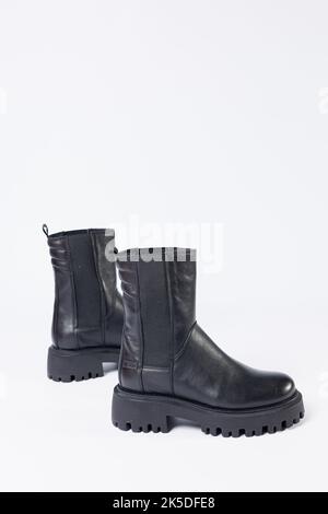 Scarpe da donna su sfondo bianco. Primo piano di stivali chelsea in pelle nera da donna su sfondo bianco. Scarpe per la città. Moda, design e fo Foto Stock
