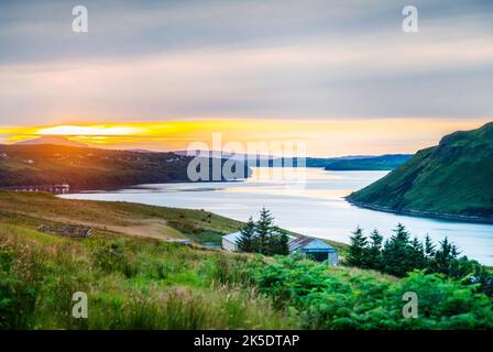 Guardando lungo Loch Morar, il sole inizia a tramontare alle 9,30pm:00 oltre l'Isola di Eigg in lontananza, calma, caldo clima di mezza estate, visto dalle strade di montagna Foto Stock