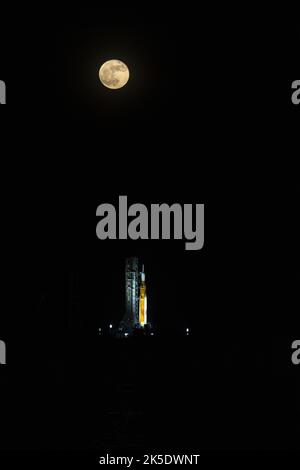 Una Luna piena è in vista dal Launch Complex 39B al Kennedy Space Center della NASA in Florida il 14 giugno 2022. Il sistema spaziale Artemis i Space Launch System (SLS) e la navicella spaziale Orion, in cima al lanciatore mobile, sono in preparazione per una prova di vestito bagnato per praticare le tempistiche e le procedure per il lancio. La prima di una serie sempre più complessa di missioni, Artemis i testerà SLS e Orion come sistema integrato prima dei voli con equipaggio per la Luna. Attraverso Artemis, la NASA atterrà la prima donna e la prima persona di colore sulla superficie lunare, spianando la strada ad una presenza lunare a lungo termine e utilizzando il Moo Foto Stock